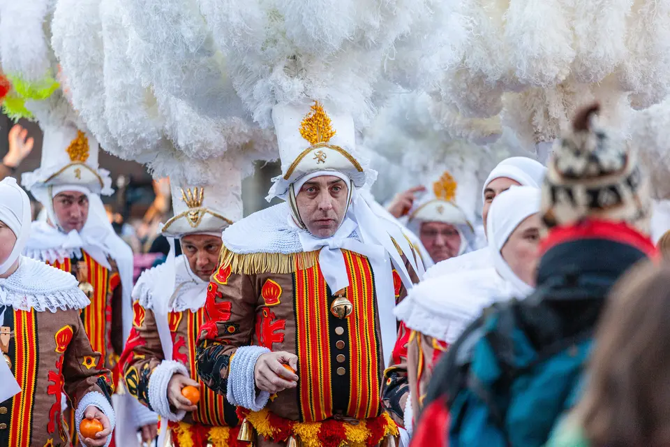 A Gille wearing the tall ostrich-feather hat, with oranges in hand, at the Carnival of Binche, 2010