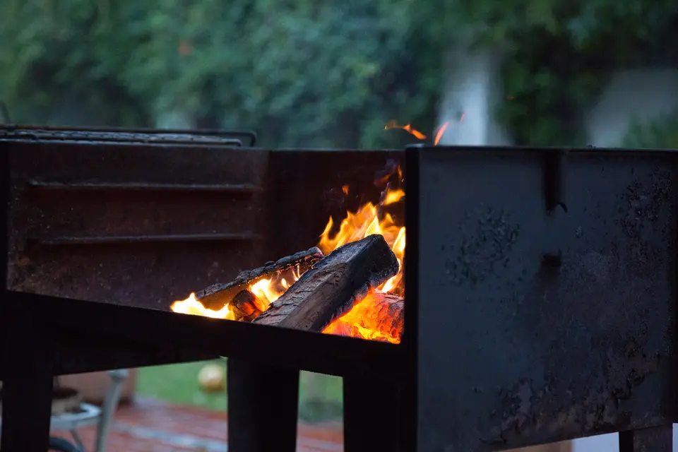 Leña quemándose hasta hacerse brasas en un braai de acero en un jardín de Ciudad del Cabo