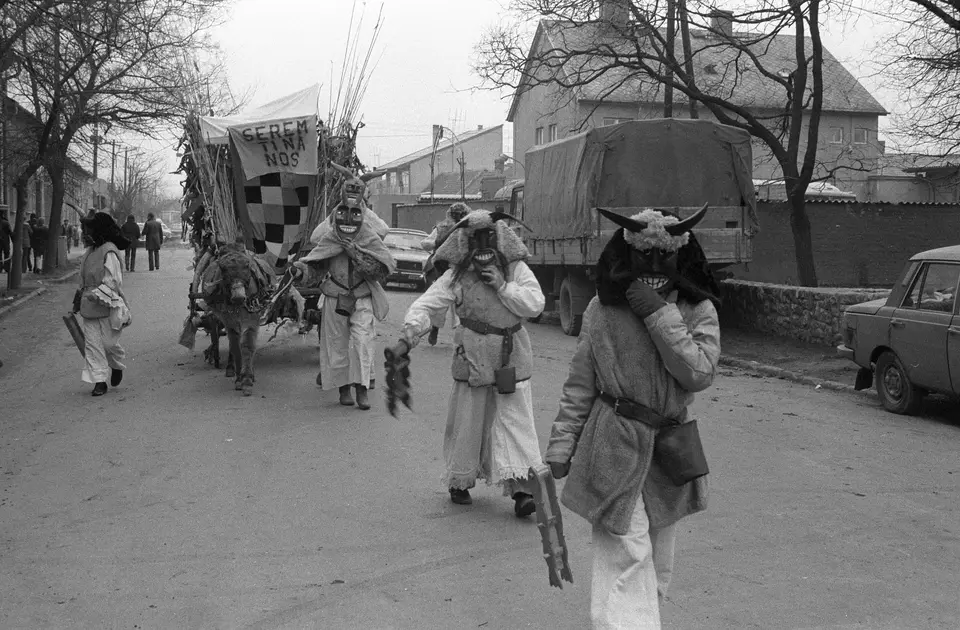 Masked Busós in sheepskins walk down a street in Mohács during the Busójárás, 1979