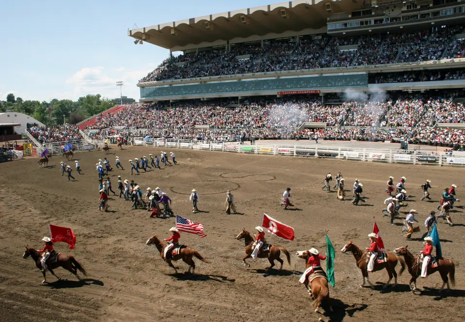 Riders carrying flags circle the rodeo arena before full grandstands on the final day of the Calgary Stampede, 2011