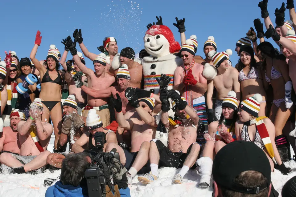 Participants in swimwear and tuques cheer beside Bonhomme at the snow bath of the Carnaval de Québec, 2010