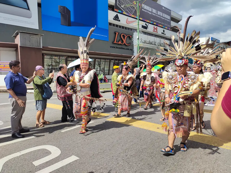羽根の被り物をつけた踊り手たちが、クチンのガワイ・ダヤックの行列で封鎖された通りを進む