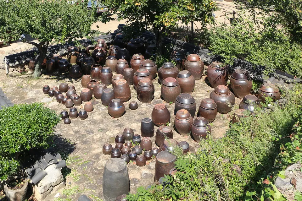 Reihen von Onggi, den koreanischen Tonkrügen, auf einer erhöhten Terrasse neben einem strohgedeckten Haus