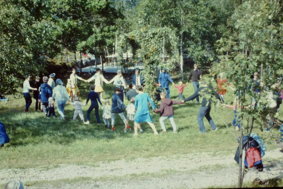 Children and adults hold hands in a ring dance at a Midsummer celebration on the Swedish west coast, 1967