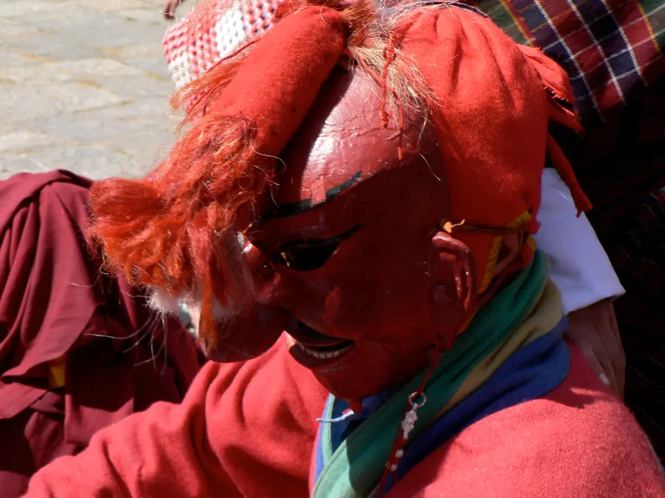 Ein Atsara beim Paro Tshechu in roter Maske mit langer Nase und rotem Haar, in ein weinrotes Gewand gehüllt