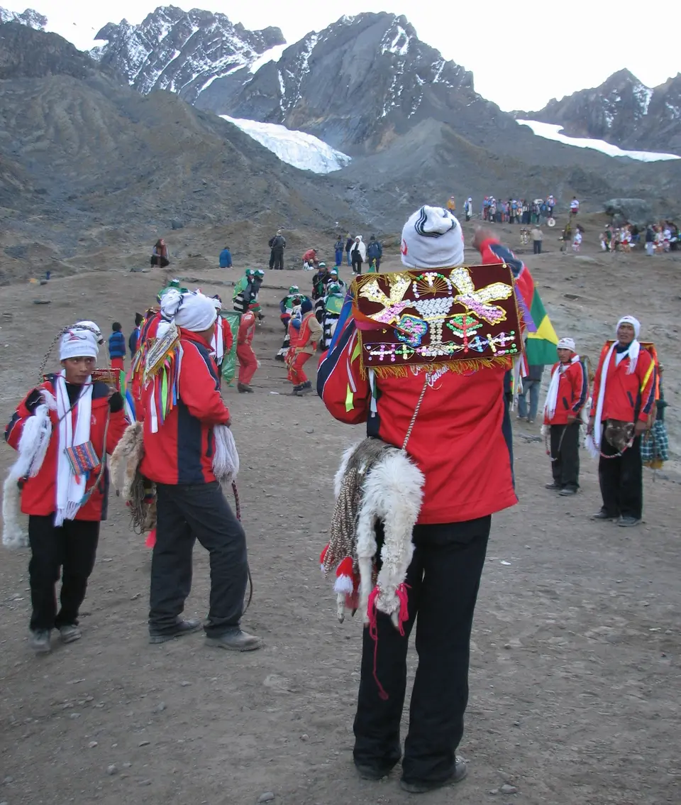 Dancers in red jackets, white-trimmed caps and woven bags on the slopes at Qoyllur Rit'i