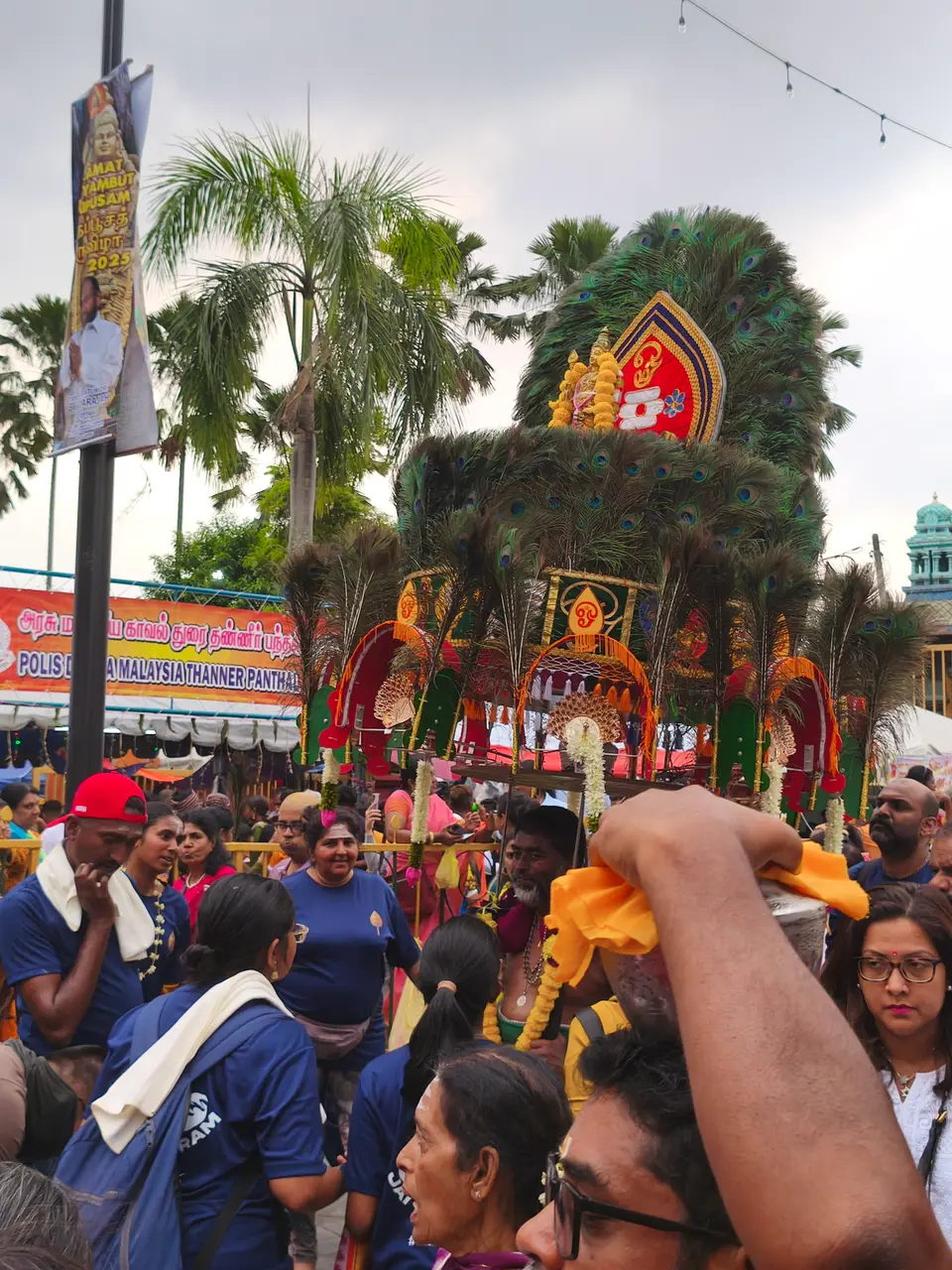 A devotee carries a large kavadi decorated with peacock feathers at Batu Caves, 2025