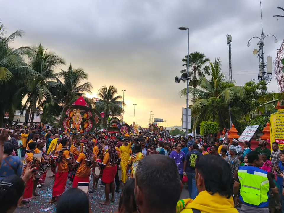 Devotees and musicians accompany decorated kavadis along the procession street at Batu Caves, 2025
