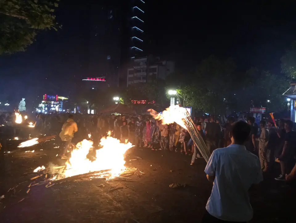 People carry burning torches past a bonfire at the Torch Festival in Shilin, Yunnan