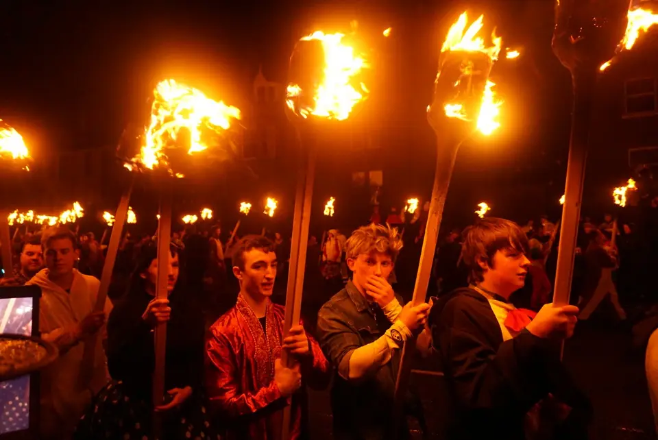 Guizers in costume carry torches down King Harald Street in the Lerwick procession, 2018