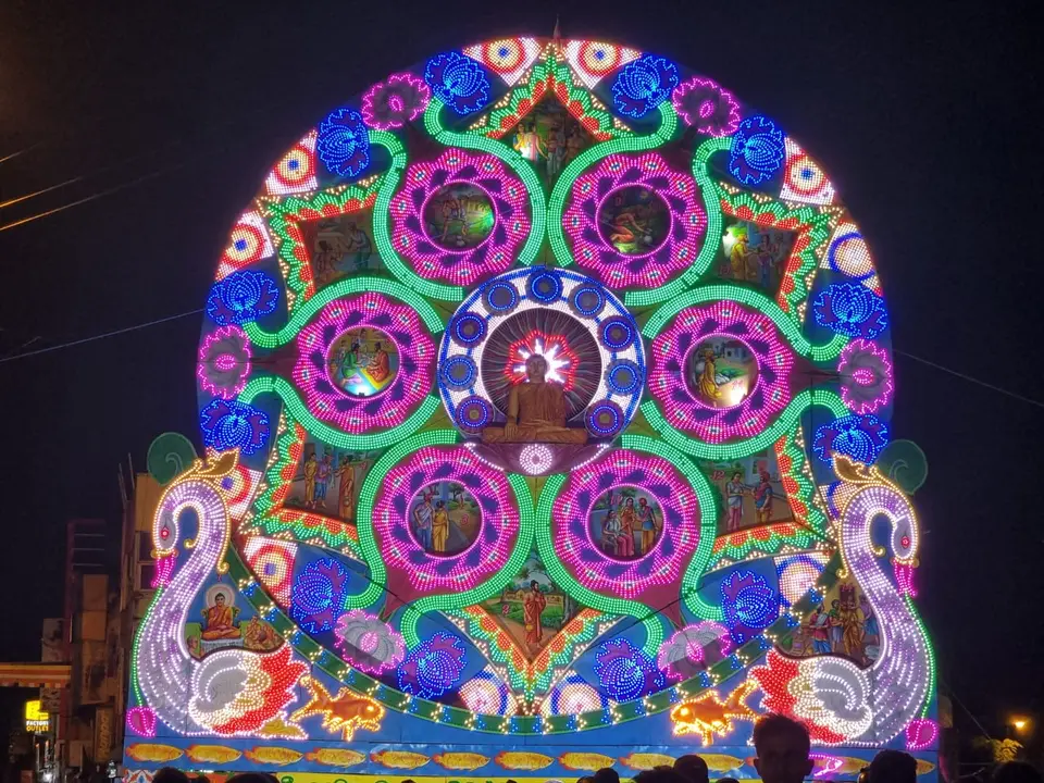 Ein Vesak-Thorana in Grandpass, Colombo: ein Fächer bemalter, beleuchteter Rundbilder, umringt von bunten Glühbirnen